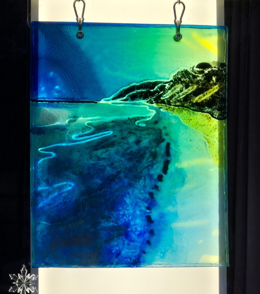 Resin painting of Bioluminescent beach at night. The resin slab is made in layers. An LED ceiling light is used for back lighting giving an even exposure to the transparent art.